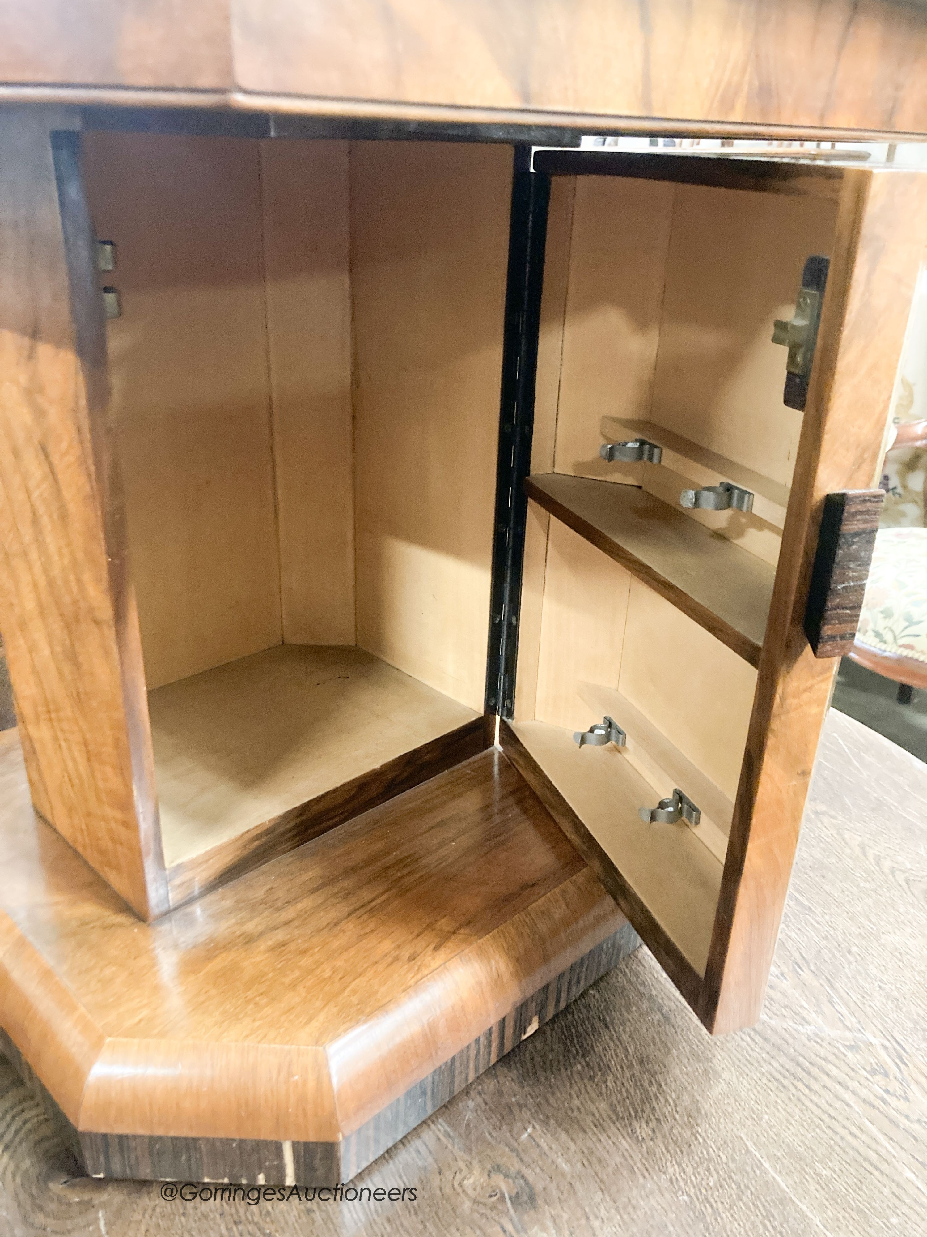 An Art Deco style octagonal figured walnut coffee table, with cupboard column, width 57cm, height 51cm